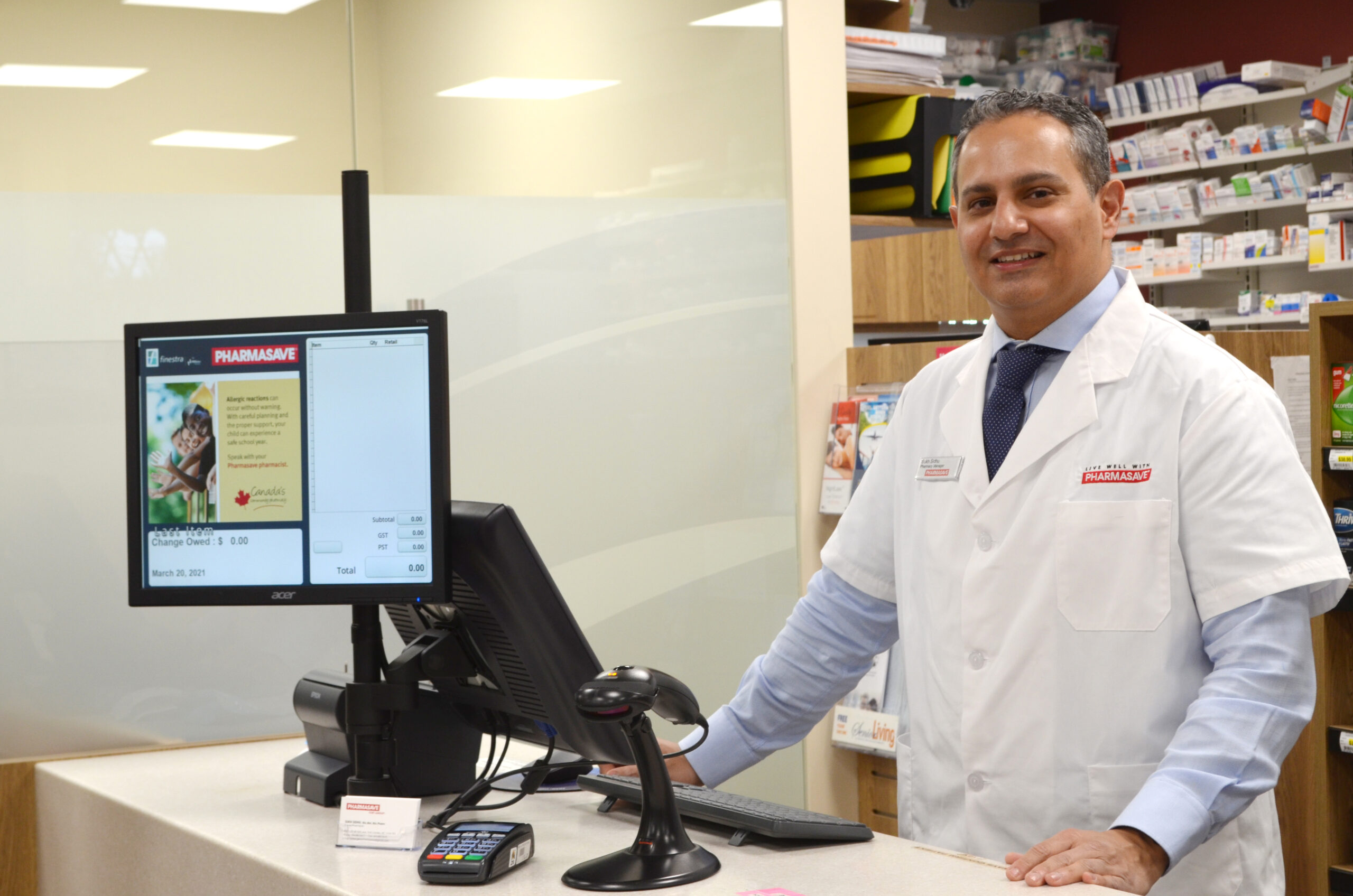 smiling pharmasave worker standing at POSitec POS system till